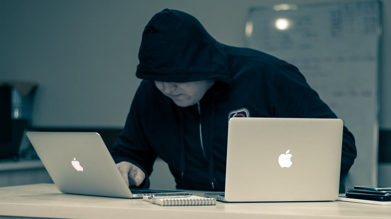 A person wearing a hood using a laptop